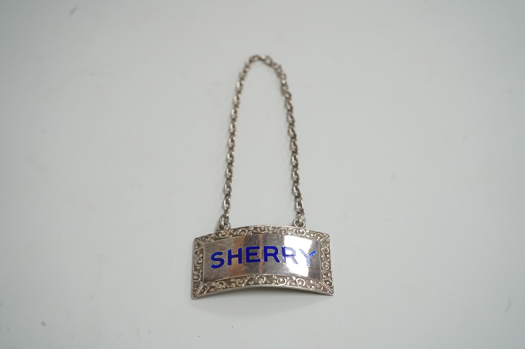 An Elizabeth II silver and blue enamel 'Sherry' wine label, by Mappin & Webb, Birmingham, 1969, width 45mm.